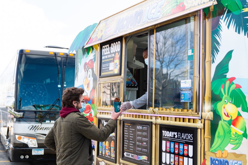 Kona Ice truck hands a shaved ice to a student.
